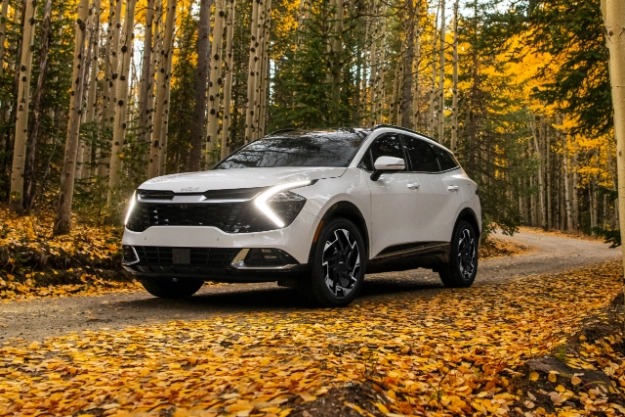 2024 Kia Sportage Driving Down A Forest During Autumn Three-Quarter View