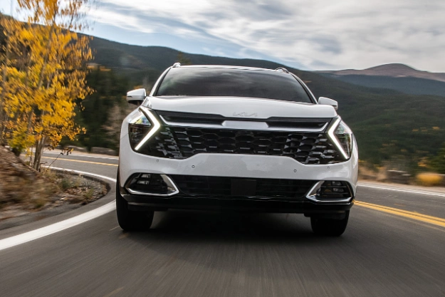 2024 Kia Sportage In White Driving On A Hill-Side Road Front-View