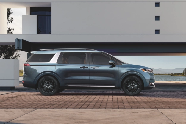 2024 Kia Carnival Parked In Front Of An Apartment Complex Side-View 