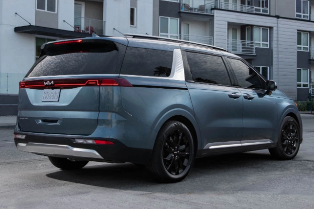 2024 Kia Carnival Parked In Front Of An Apartment Building Rear Three-Quarter View 